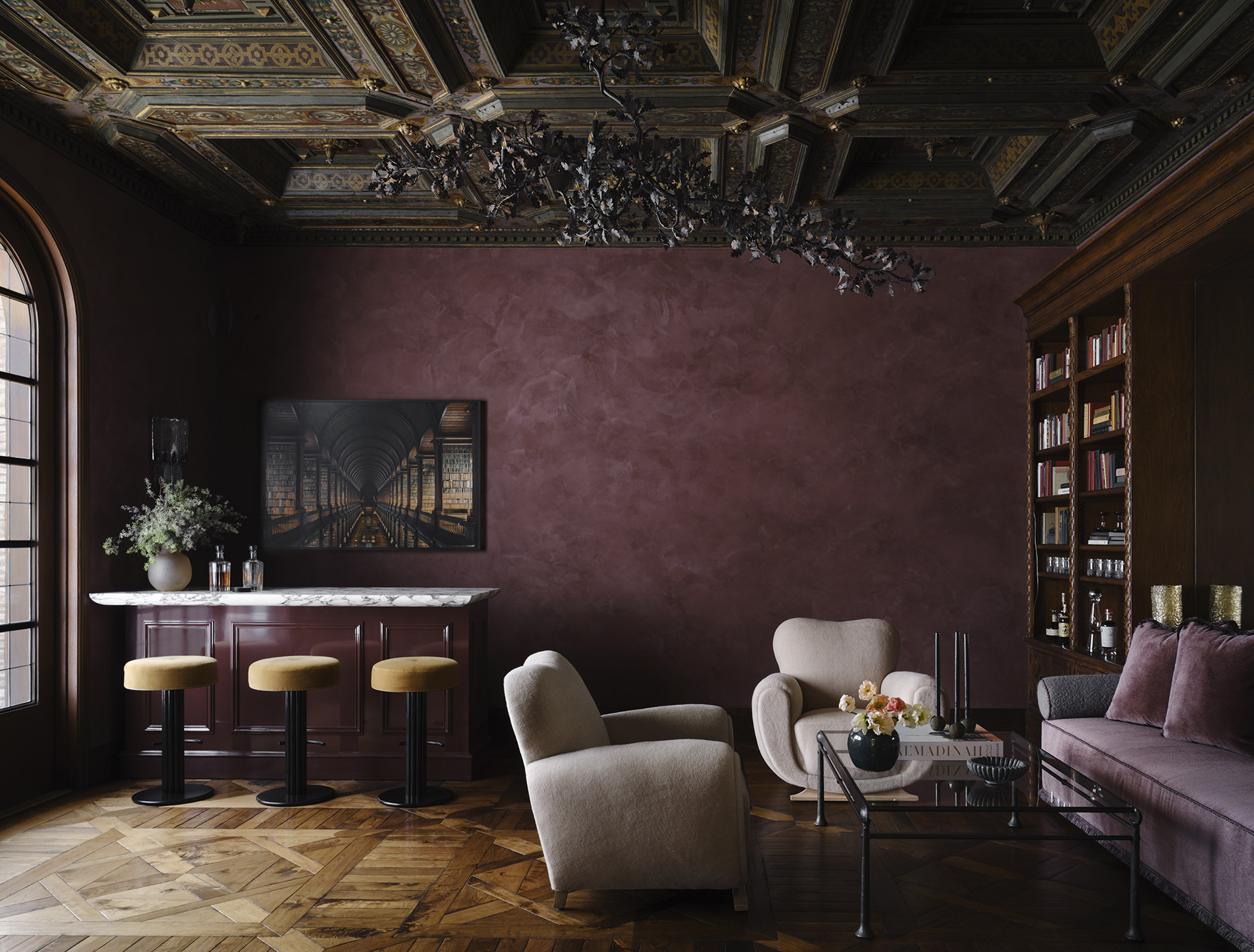 Burgundy library with upholstered chairs, sofa and stools